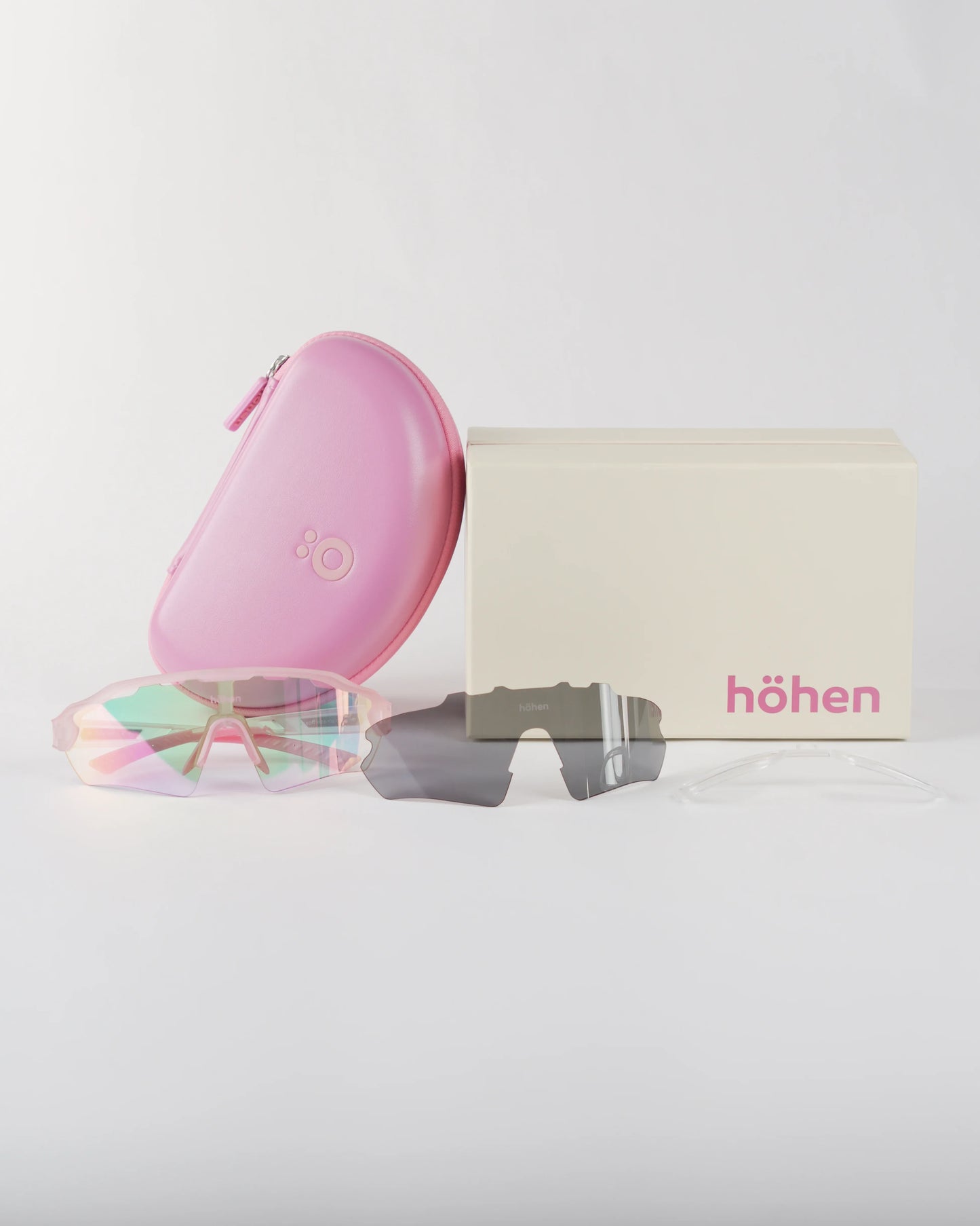 Full set of pink höhen aero sports sunglasses featuring the pink hard case, branded box, interchangeable dark lens, and optical insert frame.