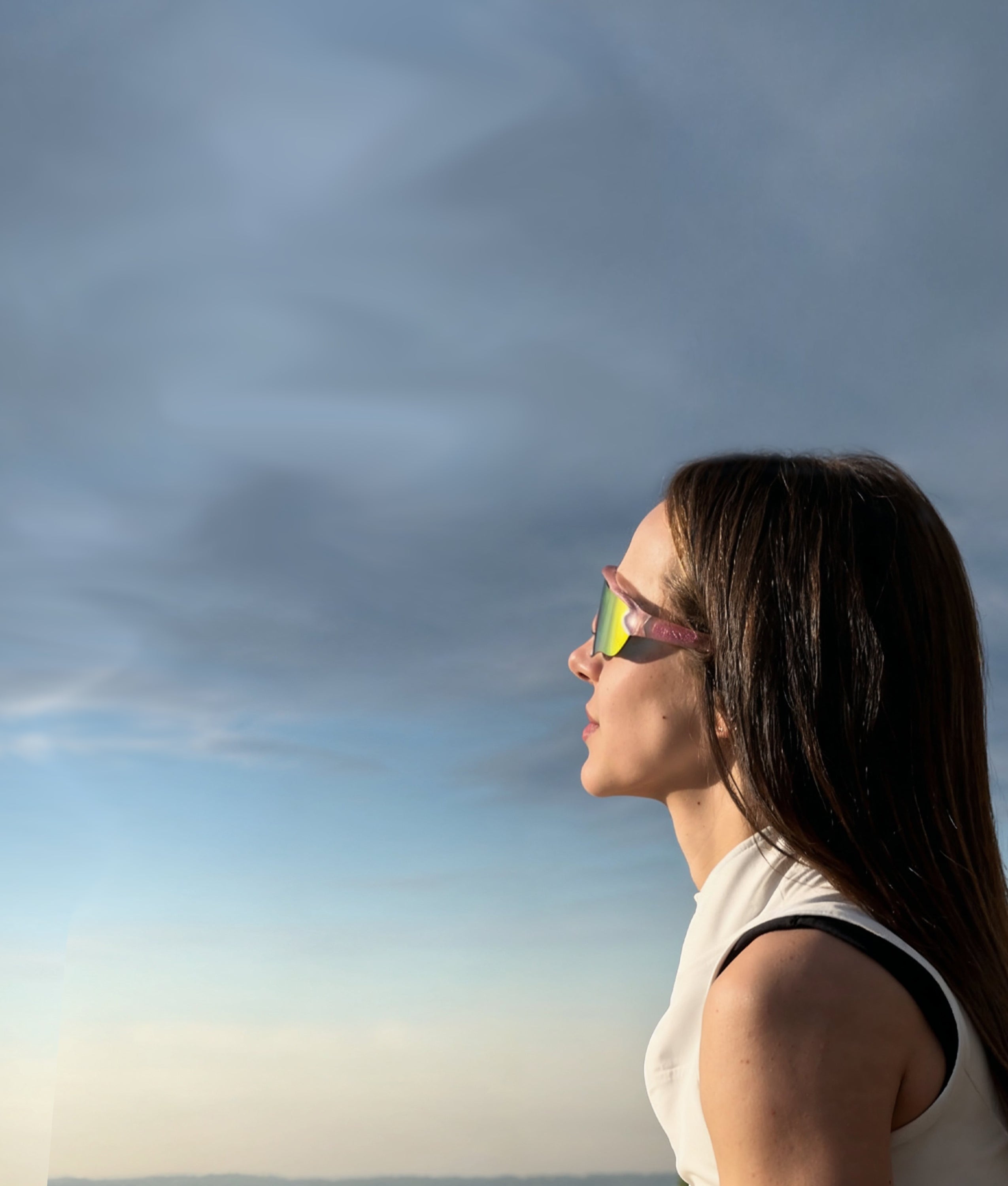 Woman wearing höhen Aero women sports sunglasses with mirrored lenses outdoors at sunset, featuring a sleek athletic design and lightweight fit.