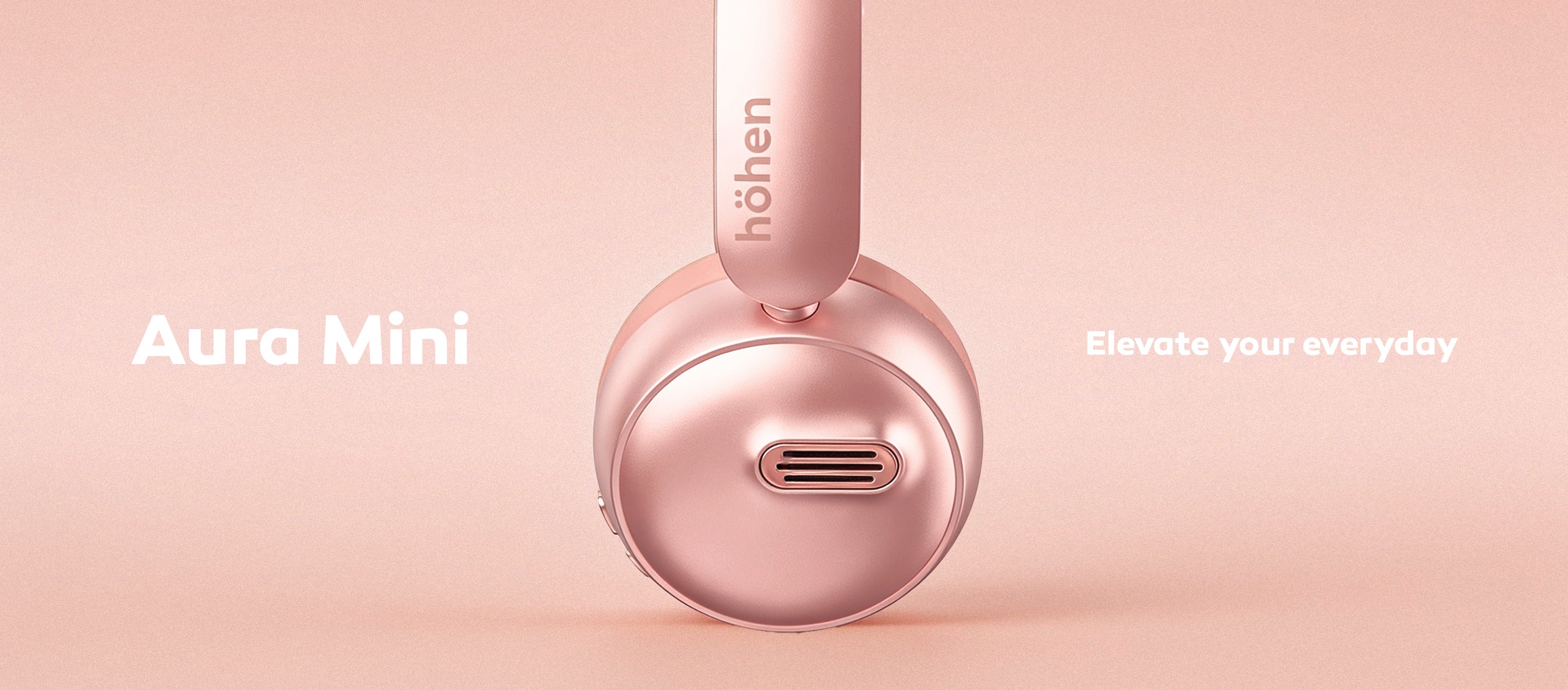Detailed side view of the rose gold höhen aura mini wireless headphones showing the minimalist branded logo on the headband against a smooth pink background