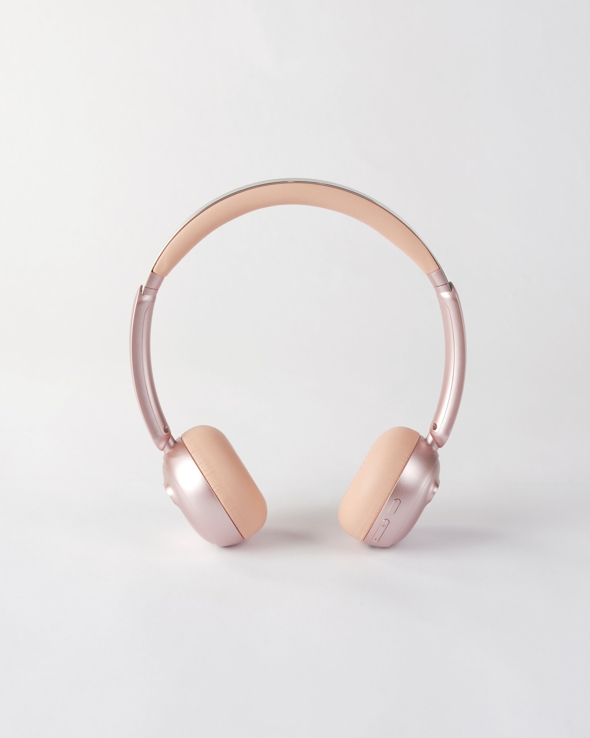 Frontal view of the höhen aura mini headphones in pink featuring a sleek metallic pink finish and minimalist control buttons