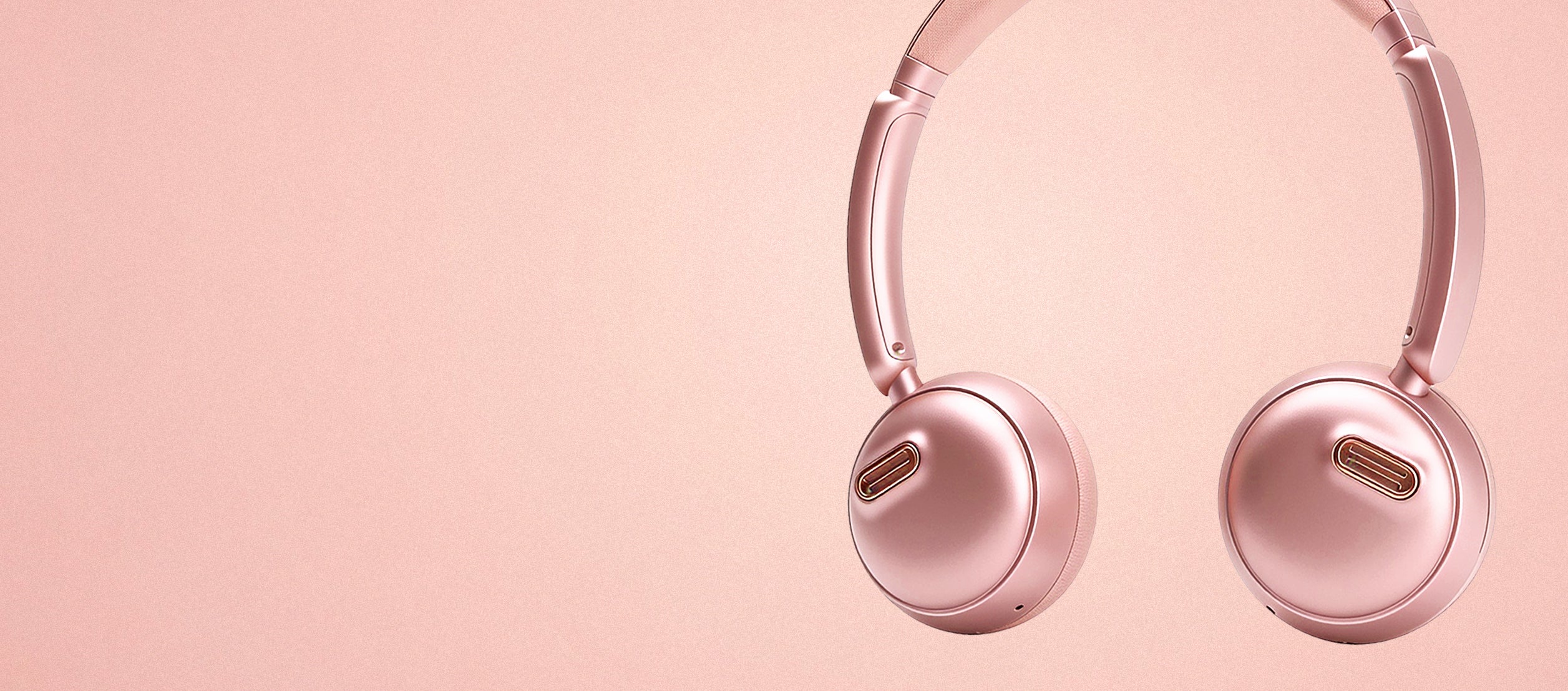 Close-up banner view of the rose gold höhen aura mini wireless headphones against a clean matching pink textured background with copy space.