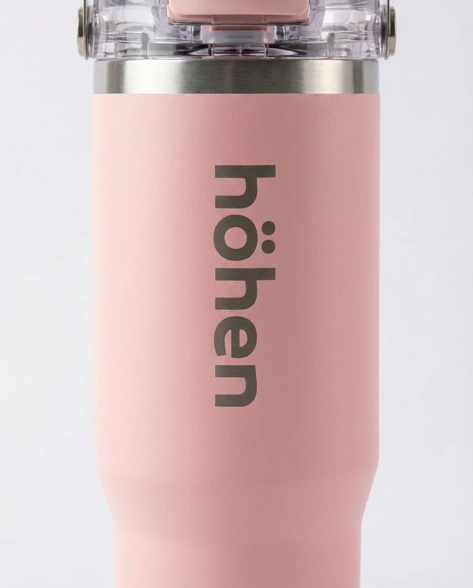 Close-up of the höhen logo on a pink Essential Tumbler with a transparent leak-proof lid.