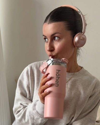 A portrait of a woman staying hydrated with the pink höhen Essential stainless steel tumbler, featuring a clean and sophisticated aesthetic