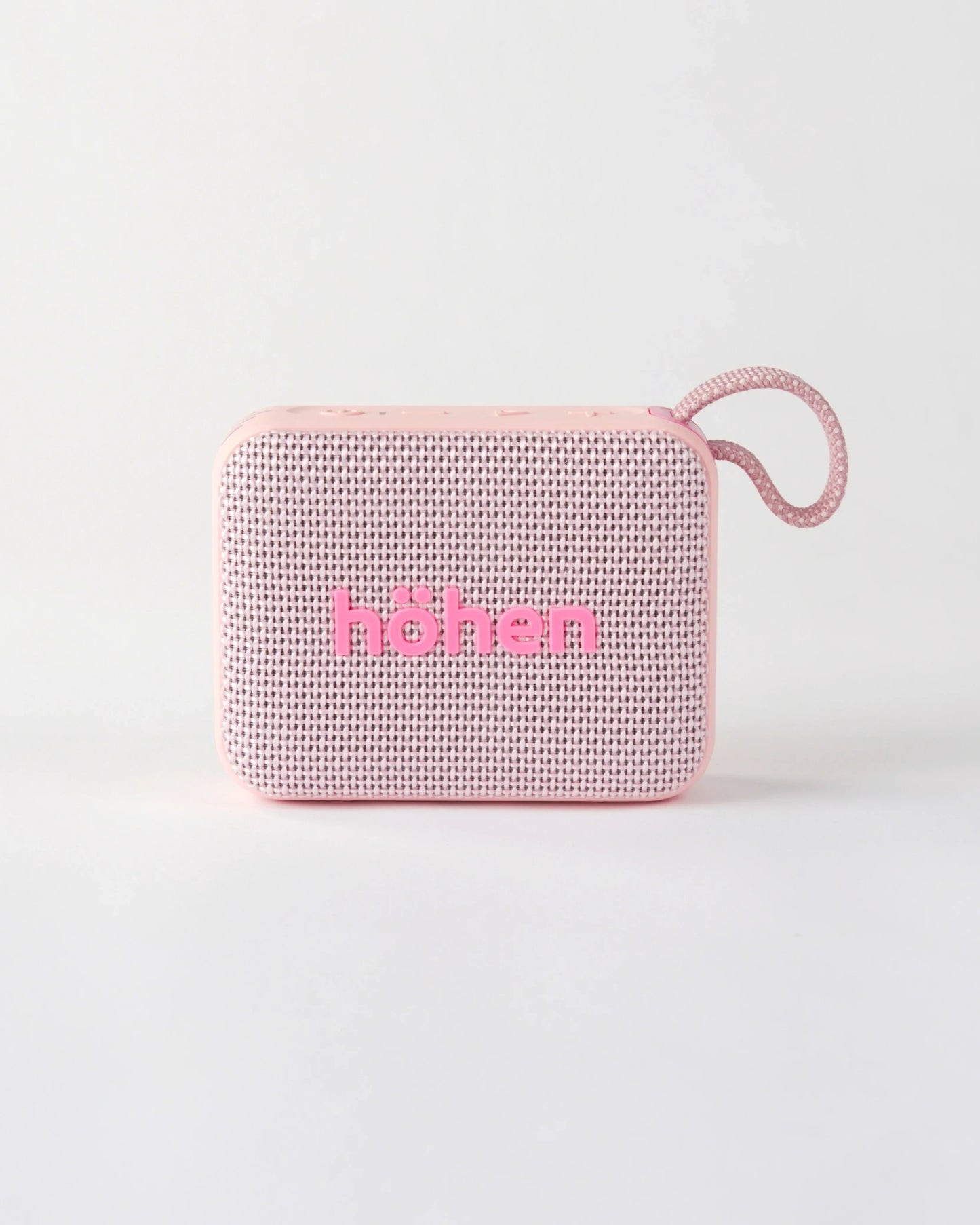 Front view of the compact höhen move portable bluetooth speaker in pale pink with a woven fabric grille and carrying loop