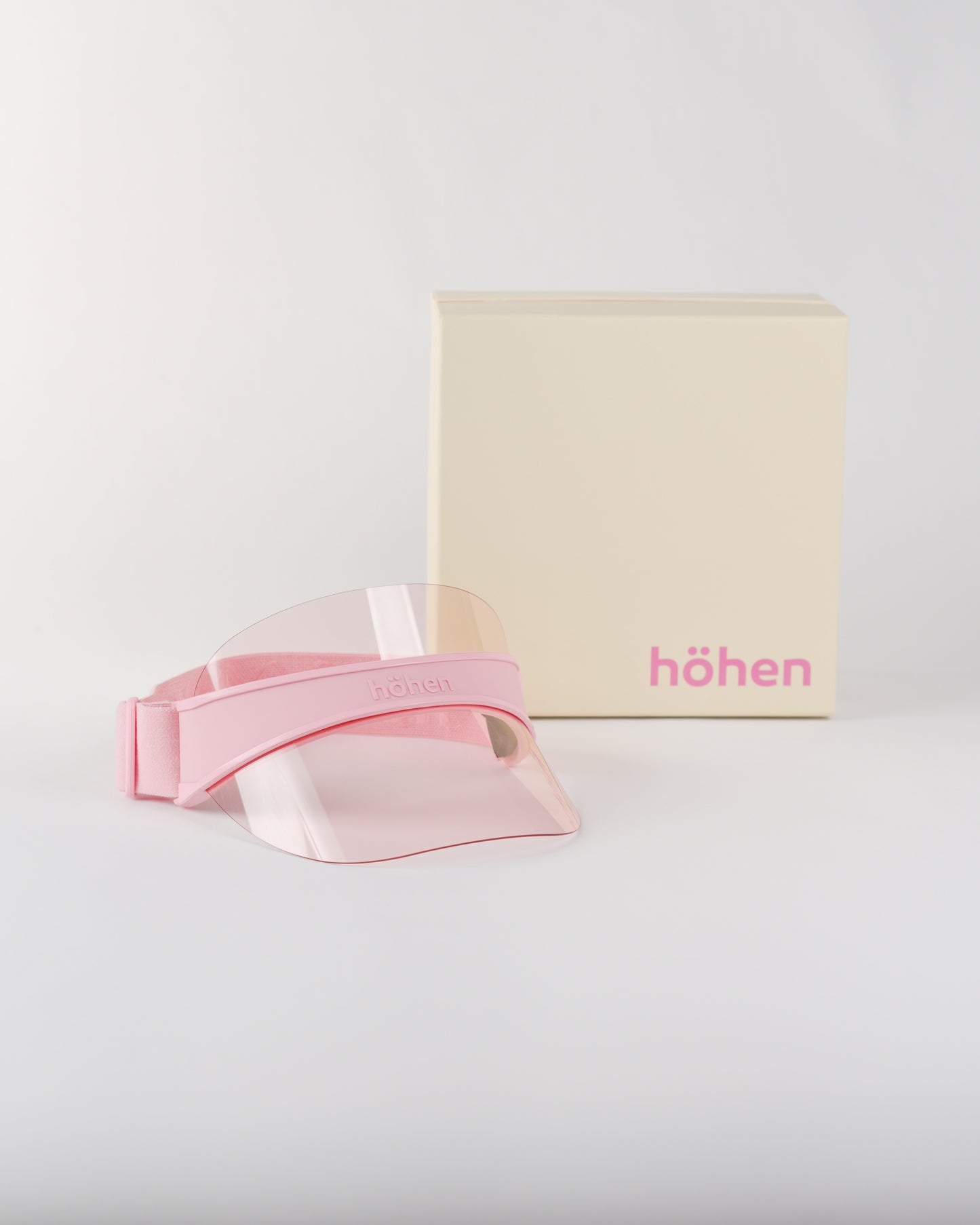 Studio shot of the höhen soleil women’s sports visor in pink featuring a clear pink transparent shield, including the premium höhen branded packaging.