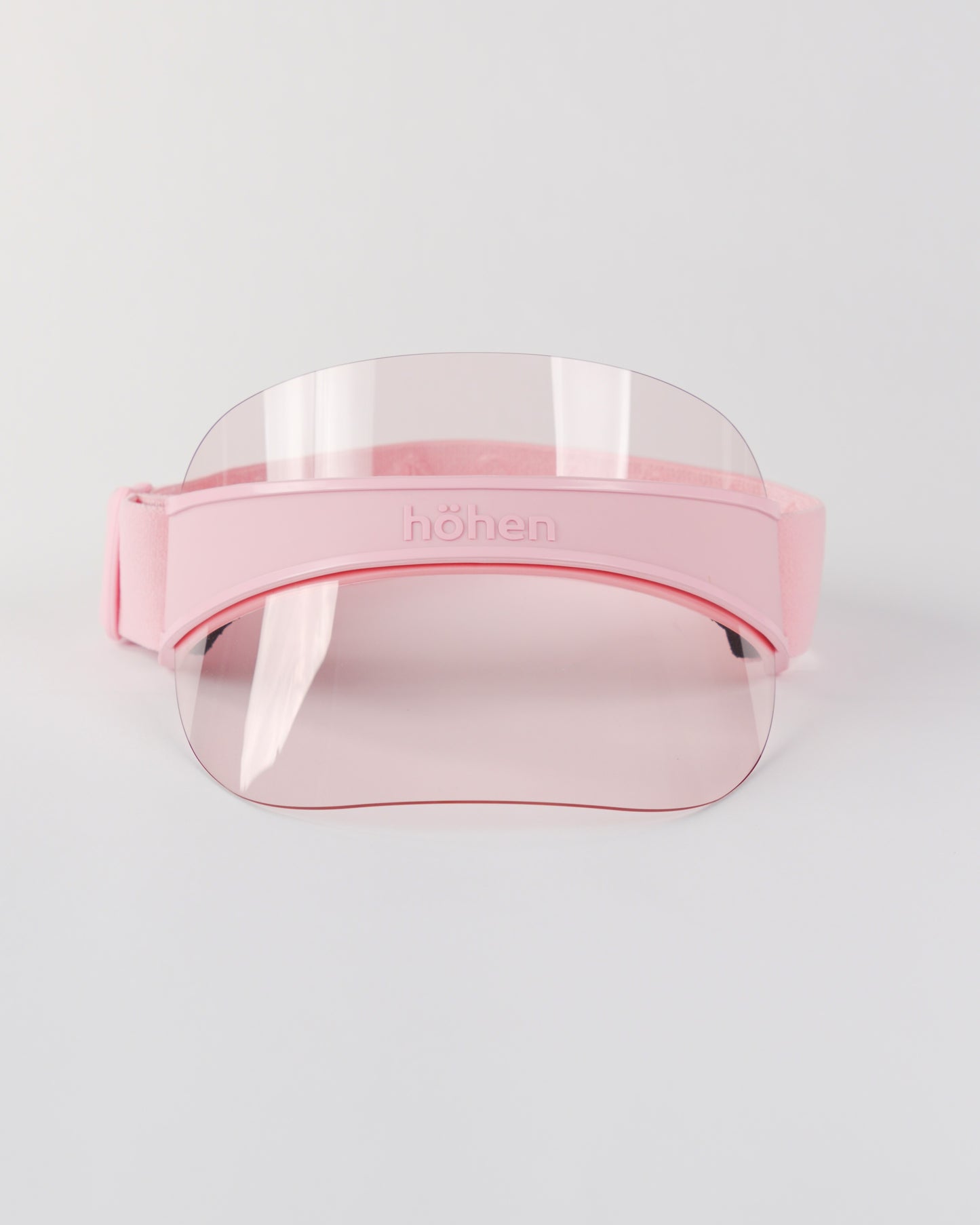 Front view of a pink höhen soleil women’s sports visor with a clear pink transparent shield and adjustable elastic band on a white background.