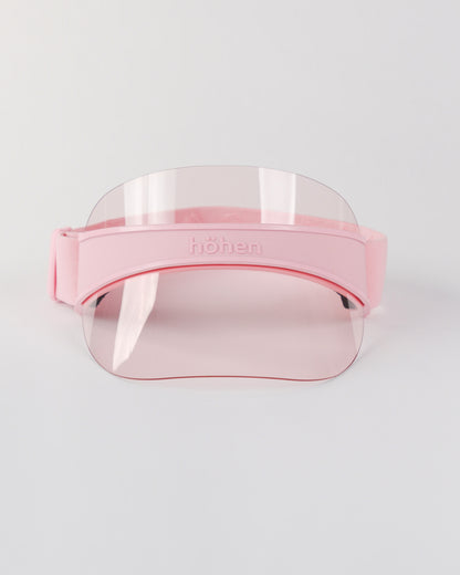 Front view of a pink höhen soleil women’s sports visor with a clear pink transparent shield and adjustable elastic band on a white background.