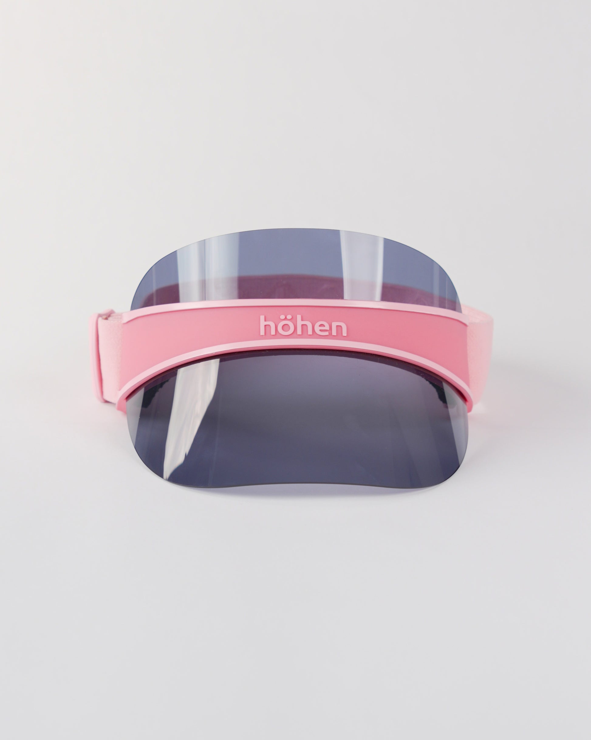 Front view of a pink höhen soleil women’s sports visor with a dark transparent shield and adjustable elastic band on a white background.