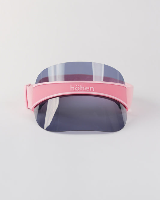 Front view of a pink höhen soleil women’s sports visor with a dark transparent shield and adjustable elastic band on a white background.