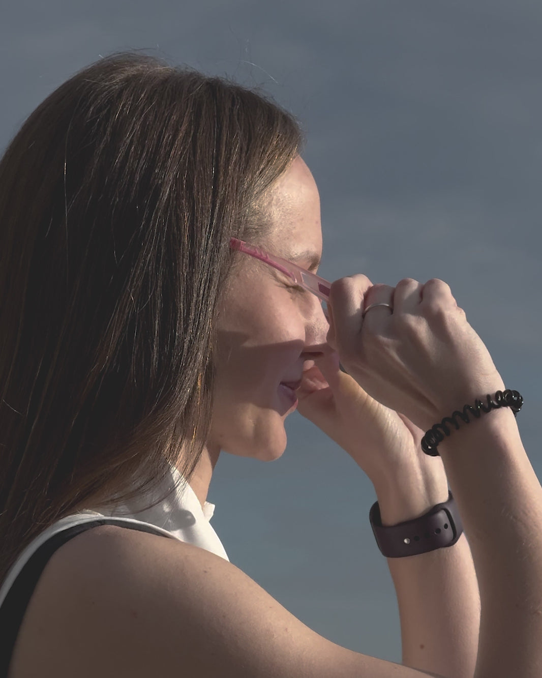 lose-up of a woman smiling and wearing pink höhen aero sports sunglasses with iridescent lenses outdoor