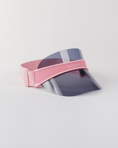 Side view of a pink höhen soleil women’s sports visor with a dark transparent shield and adjustable elastic band on a white background.